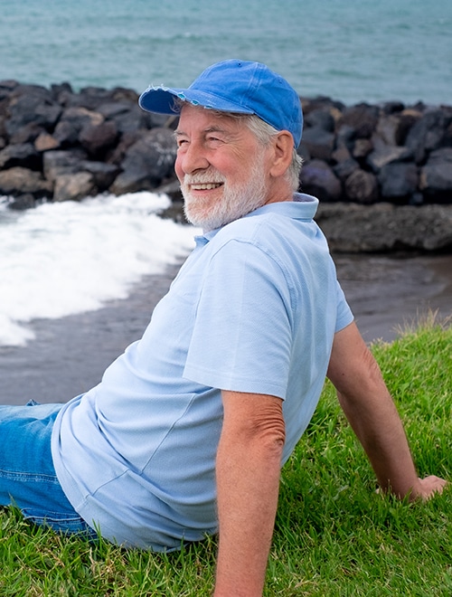 Man sitting and recovering outdoors near a beach.